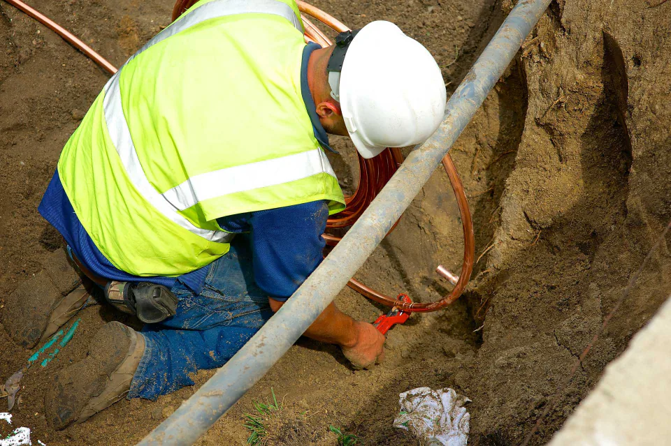 A Bob Frame Plumbing crew member repairing a water line in a trench